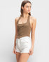 Woman wearing a brown halter top and white shorts on a light gray background