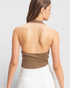 Woman wearing a brown halter top and white pants on a light gray background
