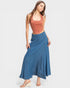 Woman wearing a rust-colored top and blue denim skirt on a white background