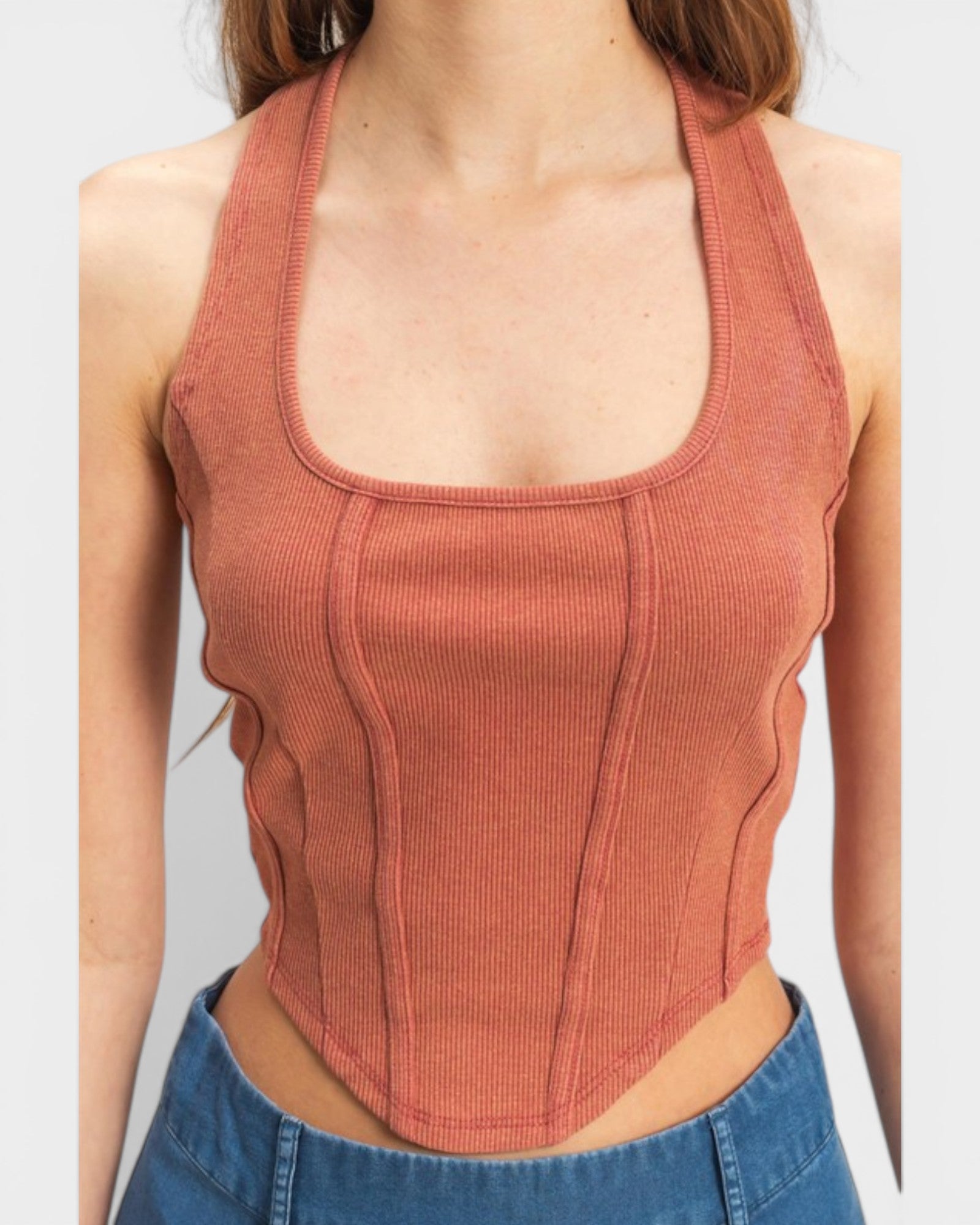 Person wearing a rust-colored ribbed tank top with a plain background