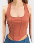 Person wearing a rust-colored ribbed tank top with a plain background