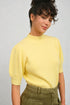 Woman wearing a yellow sweater against a plain background