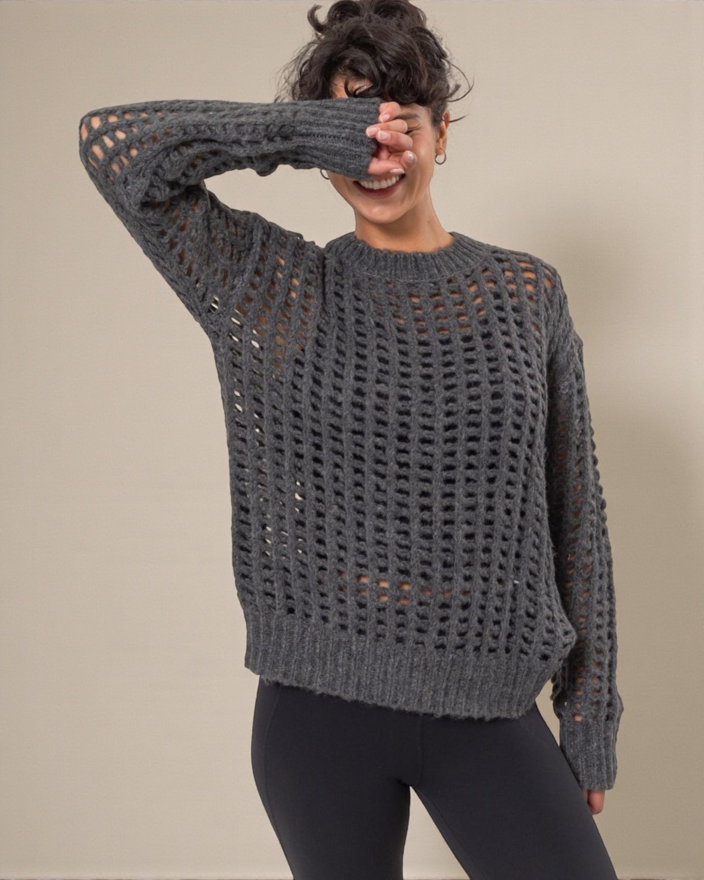 Person wearing a gray knit sweater with a textured pattern against a plain background