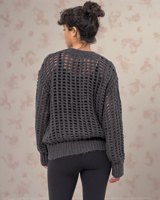 Person wearing a gray knit sweater with a floral patterned background