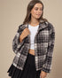 Woman wearing a plaid jacket over a white top and black skirt on a beige background