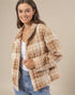 Woman wearing a beige and brown patterned jacket on a beige background