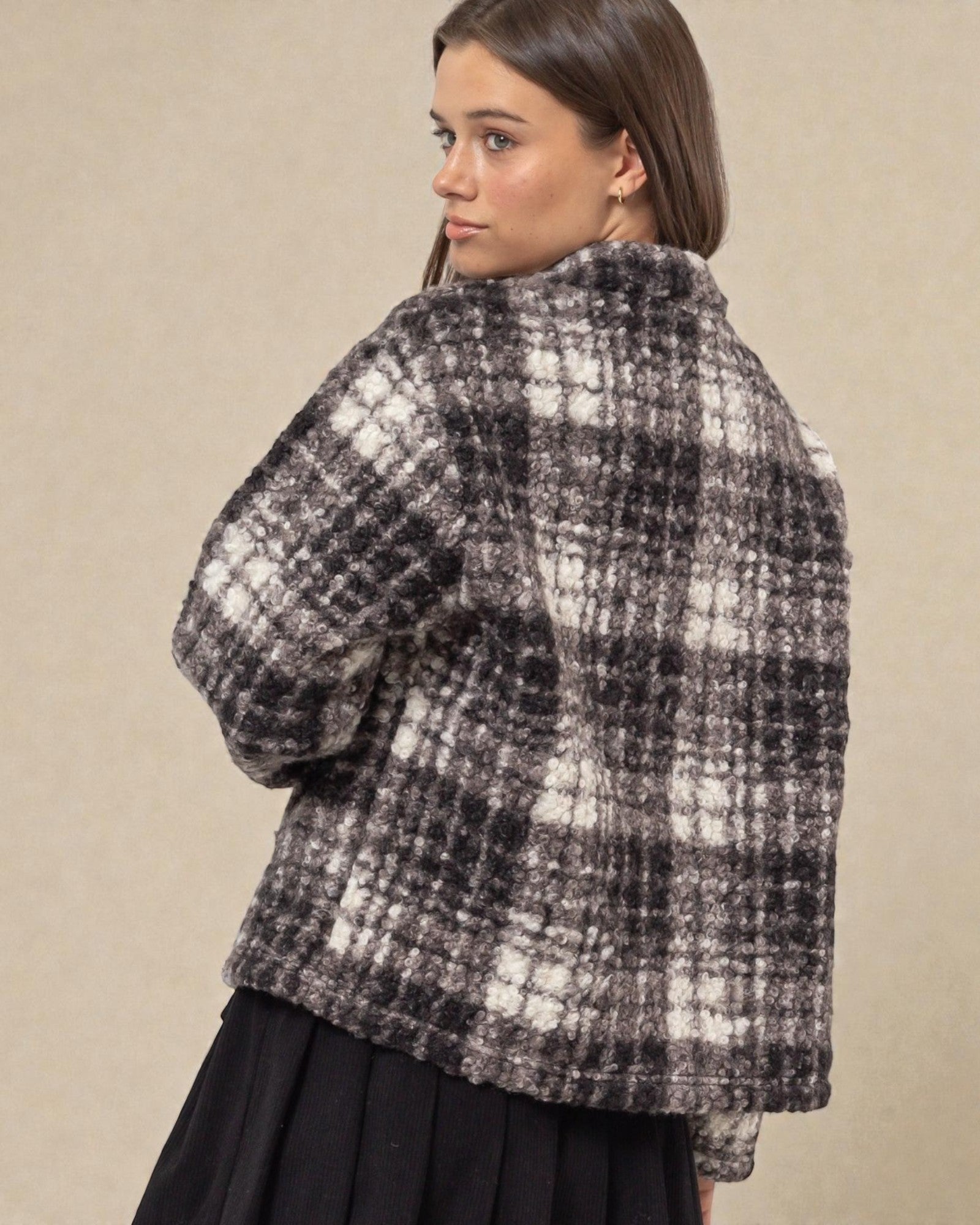 Woman wearing a black and white checkered jacket on a beige background