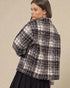 Woman wearing a black and white checkered jacket on a beige background