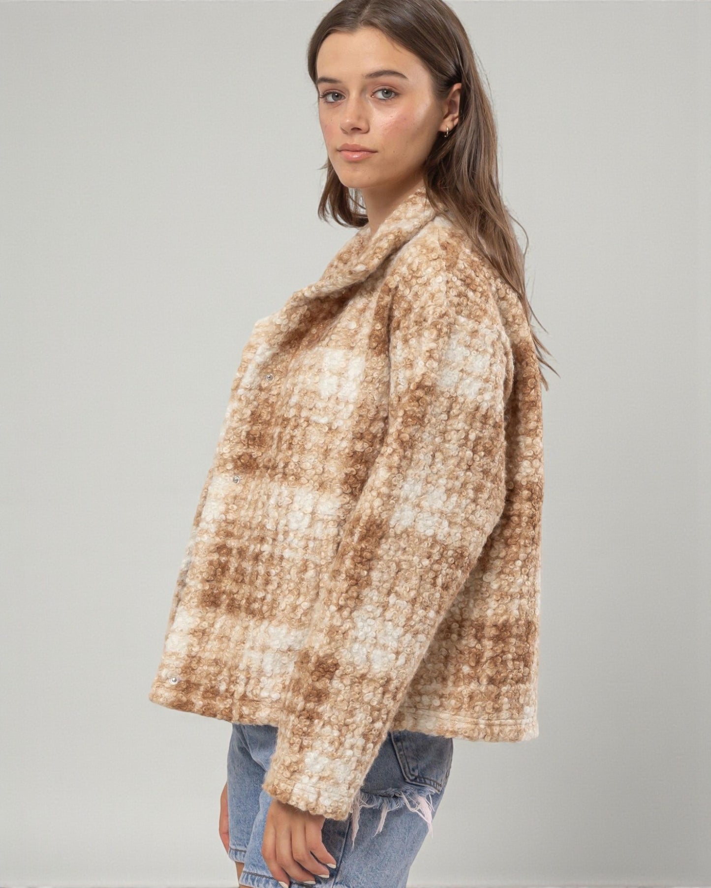 Woman wearing a brown and beige checkered coat on a gray background