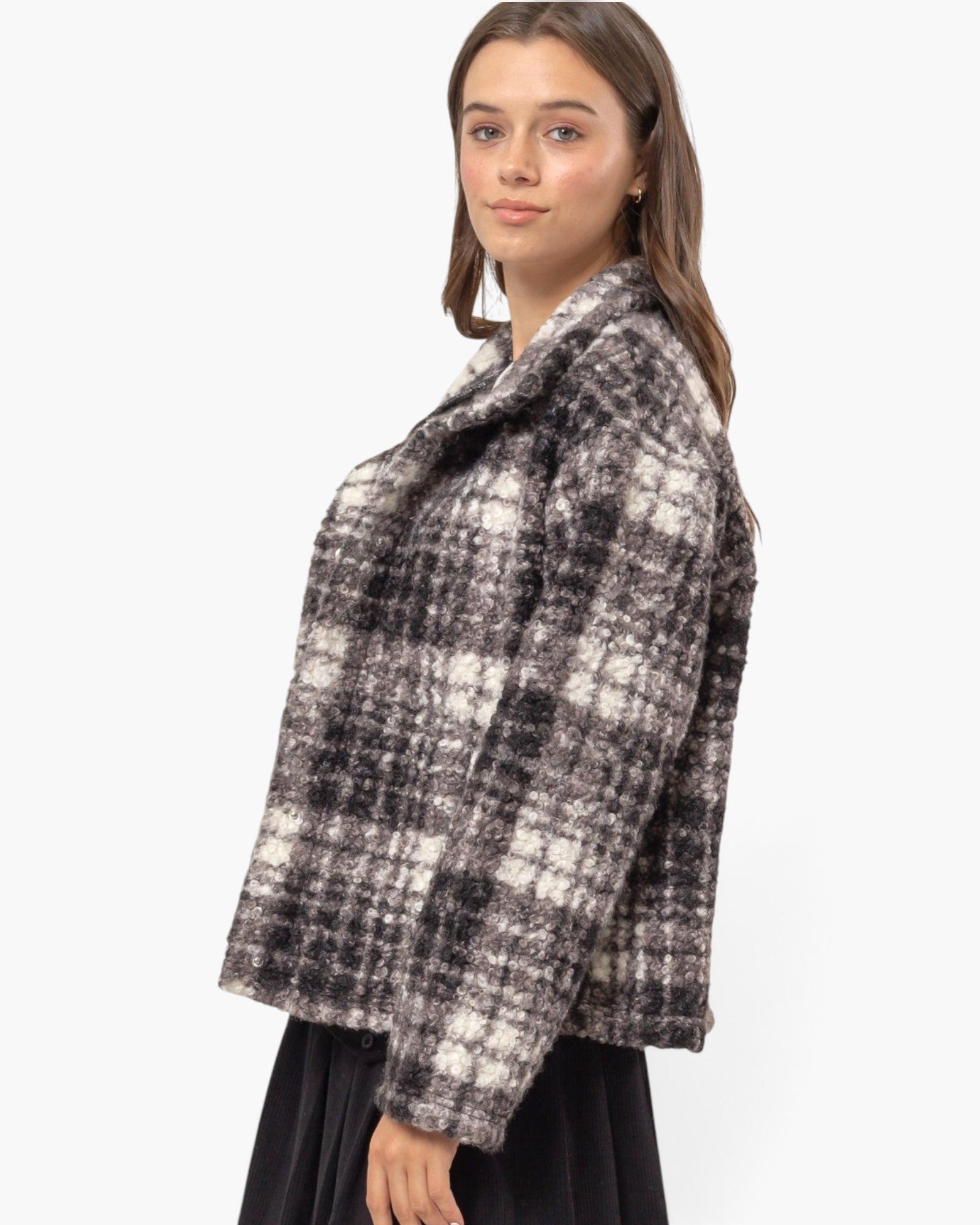 A woman modeling a fuzzy black and off-white plaid cropped jacket against a plain white background.