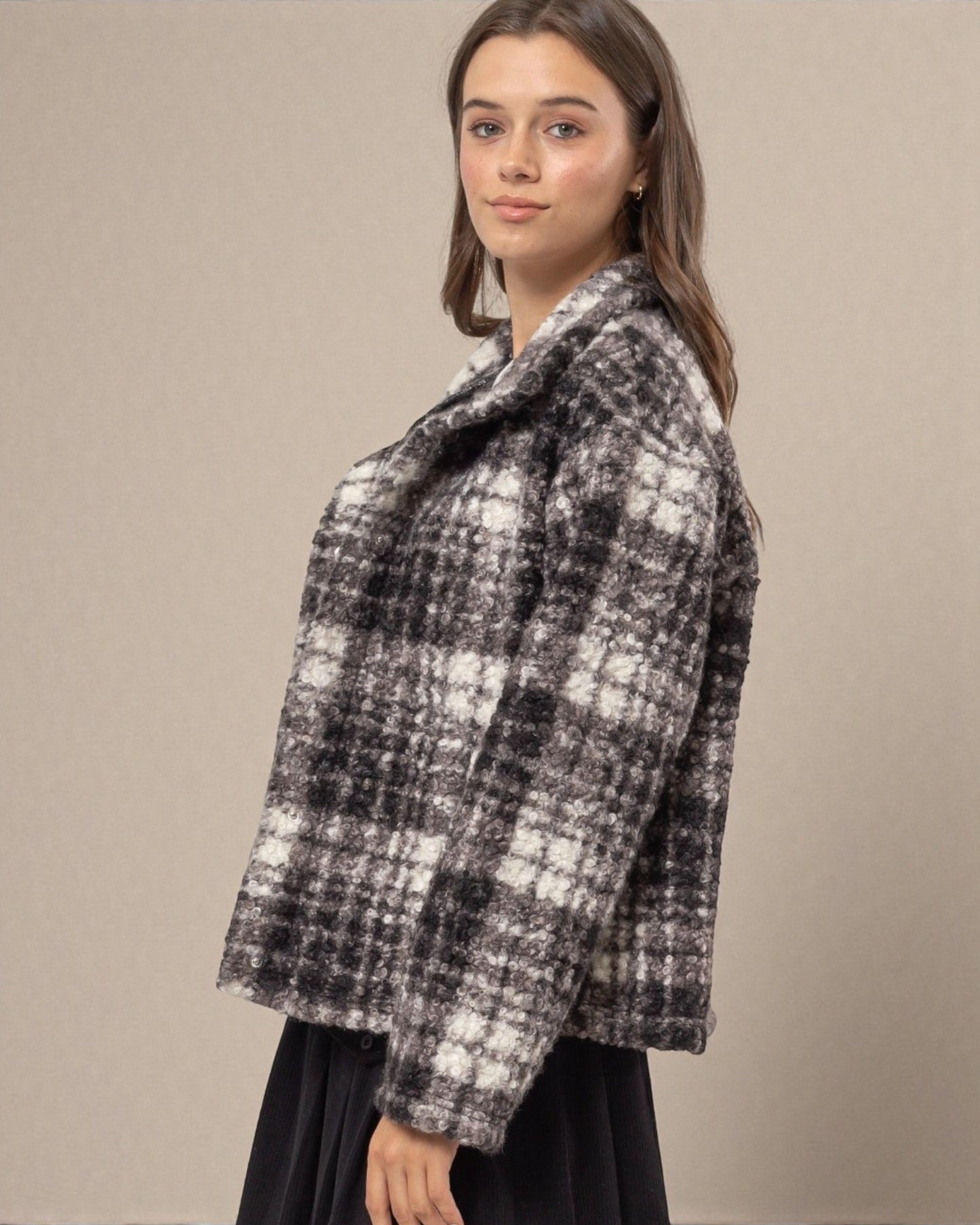Woman wearing a black and white checkered coat against a beige background