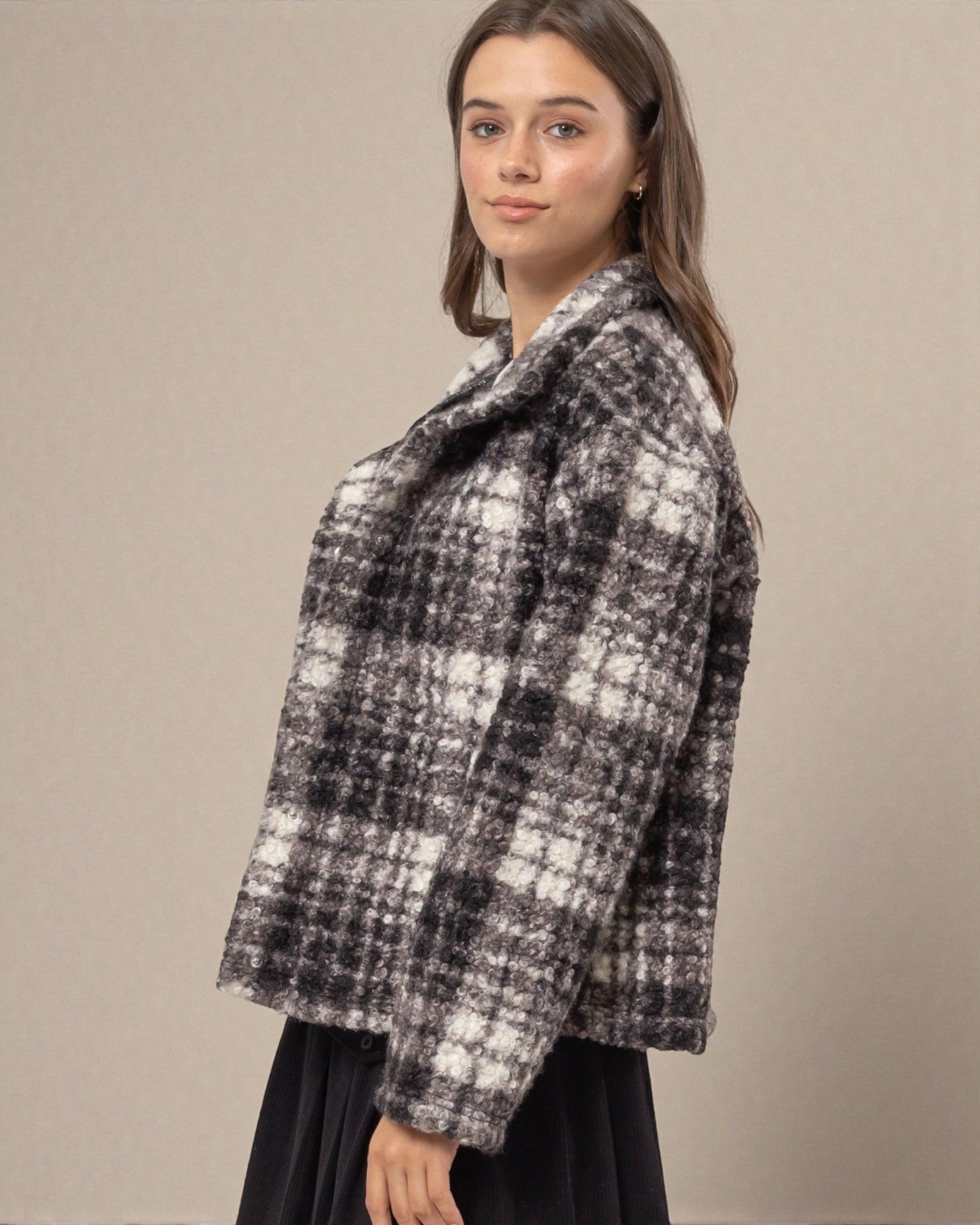 Woman wearing a black and white checkered coat against a beige background