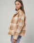 Woman wearing a brown and beige checkered coat on a gray background