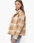 A woman wearing a fuzzy, oversized plaid jacket in beige and brown tones, paired with light-wash blue jeans, photographed against a clean white background.