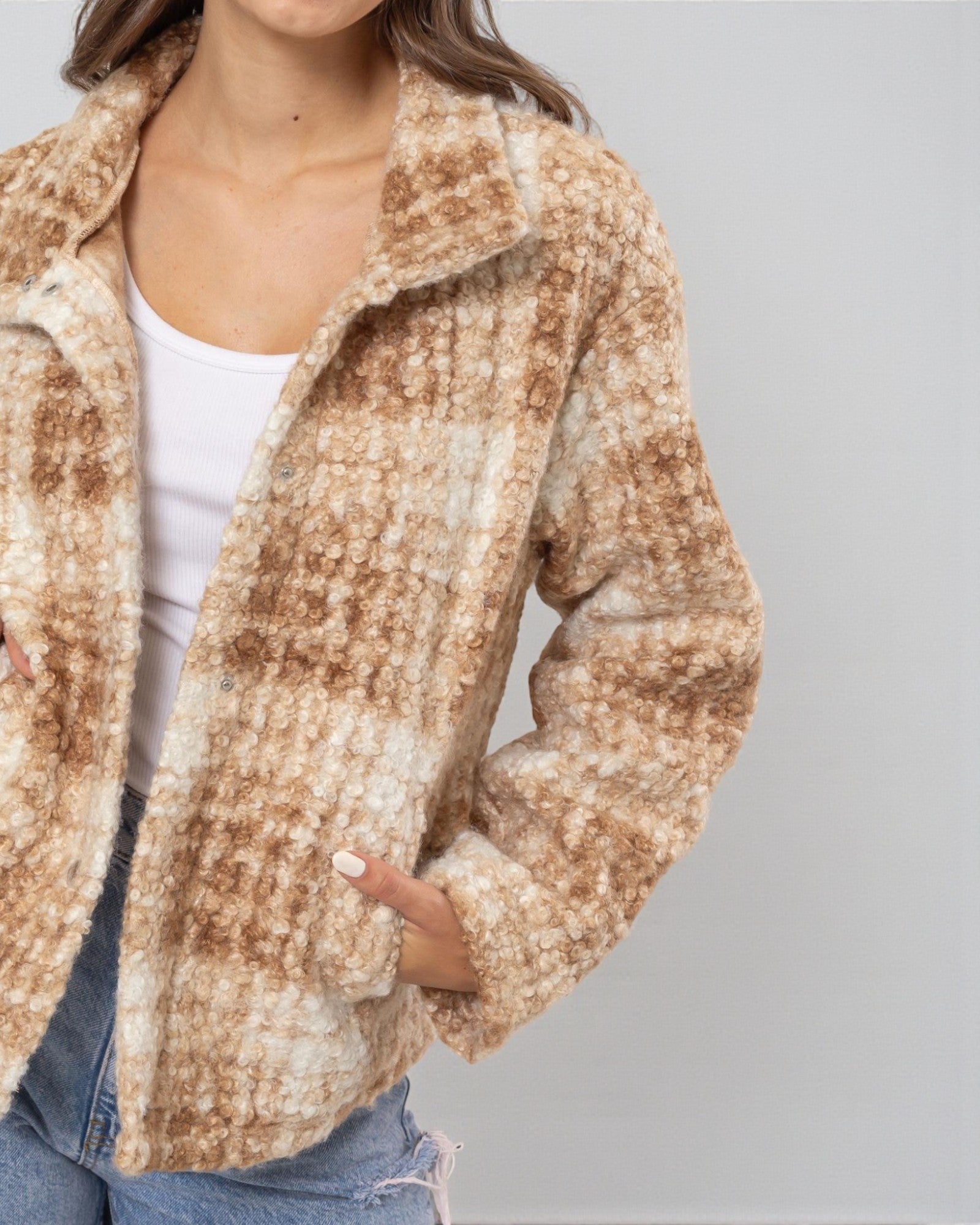 Person wearing a patterned jacket against a plain background