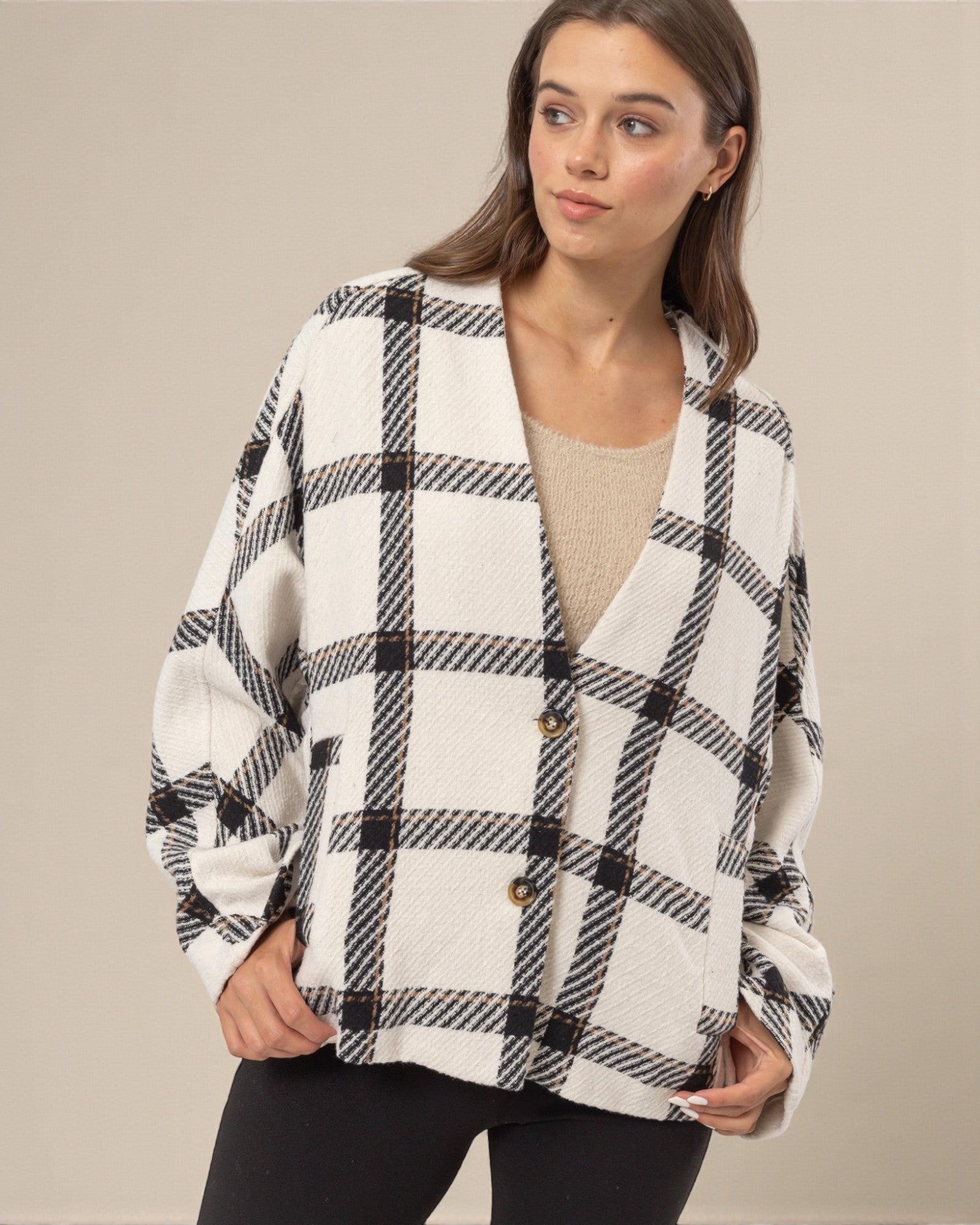 Woman wearing a black and white checkered jacket against a beige background