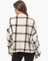 A woman shown from the back wearing a cream-colored cropped jacket with a black and gray plaid pattern, paired with black pants, against a plain white background.