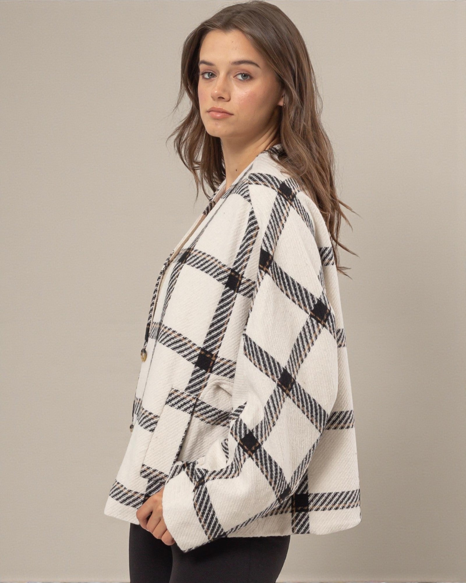 Woman wearing a black and white checkered coat against a plain background