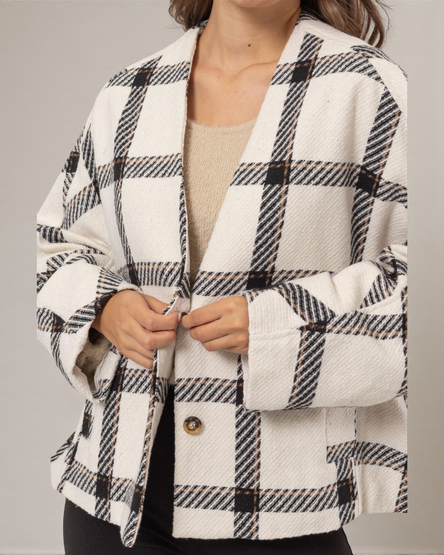 Person wearing a black and white checkered coat on a gray background