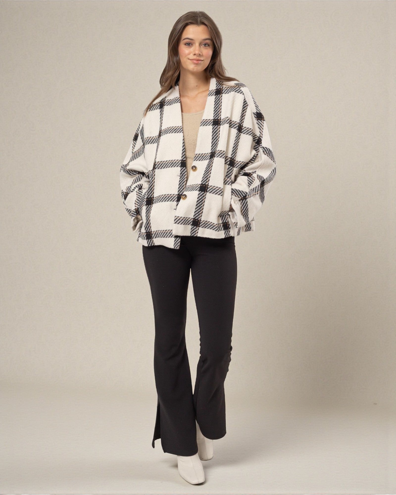 Woman wearing a black and white checkered jacket with black pants on a plain background