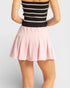 Person wearing a black and white striped top and pink skirt on a light gray background
