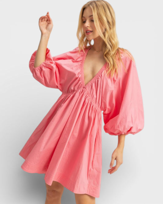 Woman wearing a pink dress with balloon sleeves on a white background