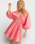 Woman wearing a pink dress with balloon sleeves on a white background