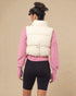 Person wearing a white puffer vest over a pink sweater on a beige background
