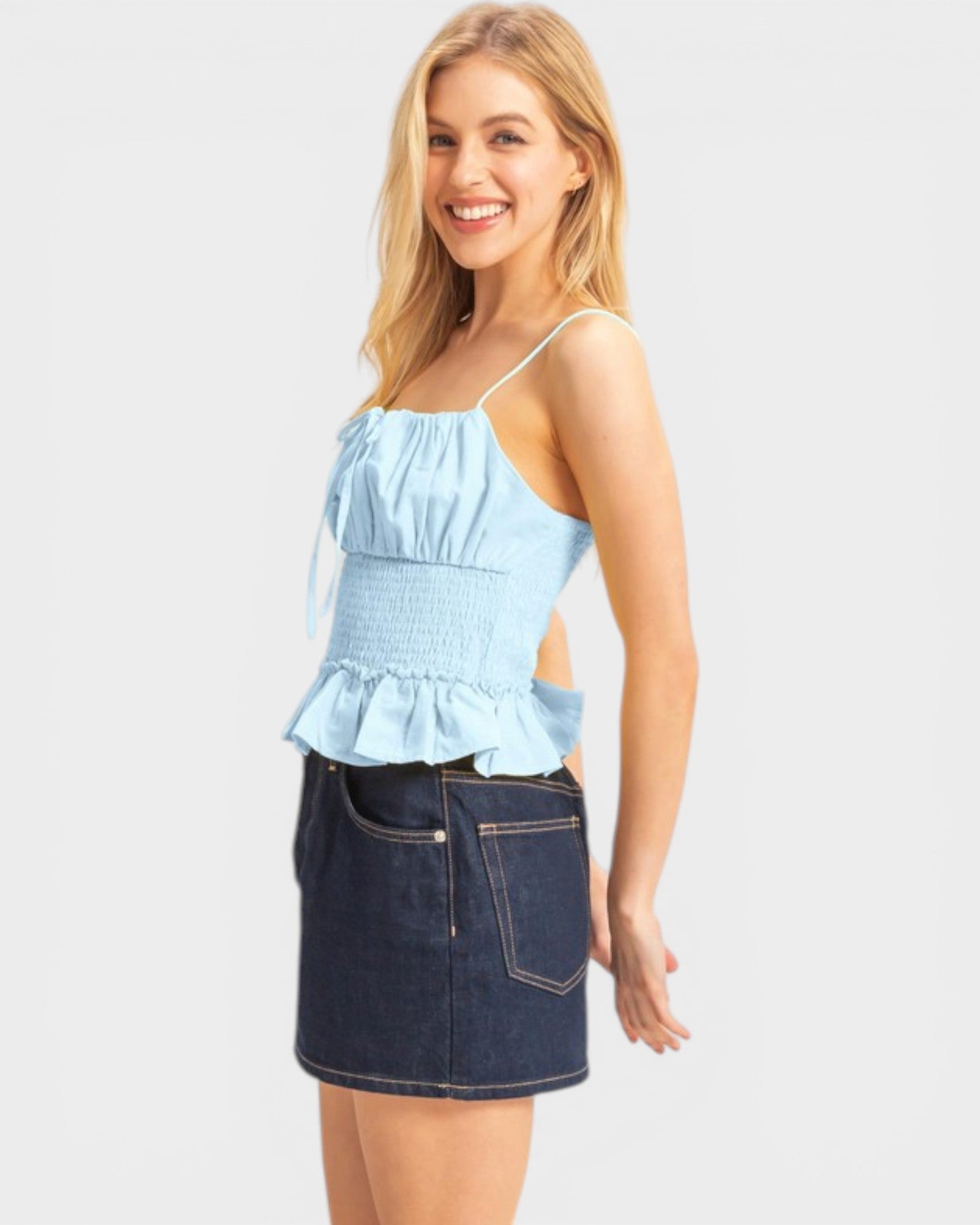Woman wearing a light blue top and dark blue denim skirt on a white background