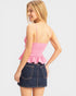 Woman wearing a pink peplum top and denim skirt on a white background