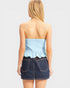 Woman wearing a light blue peplum top and dark denim skirt on a white background