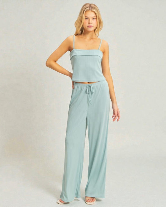 Woman wearing a light blue top and wide-leg pants on a plain background