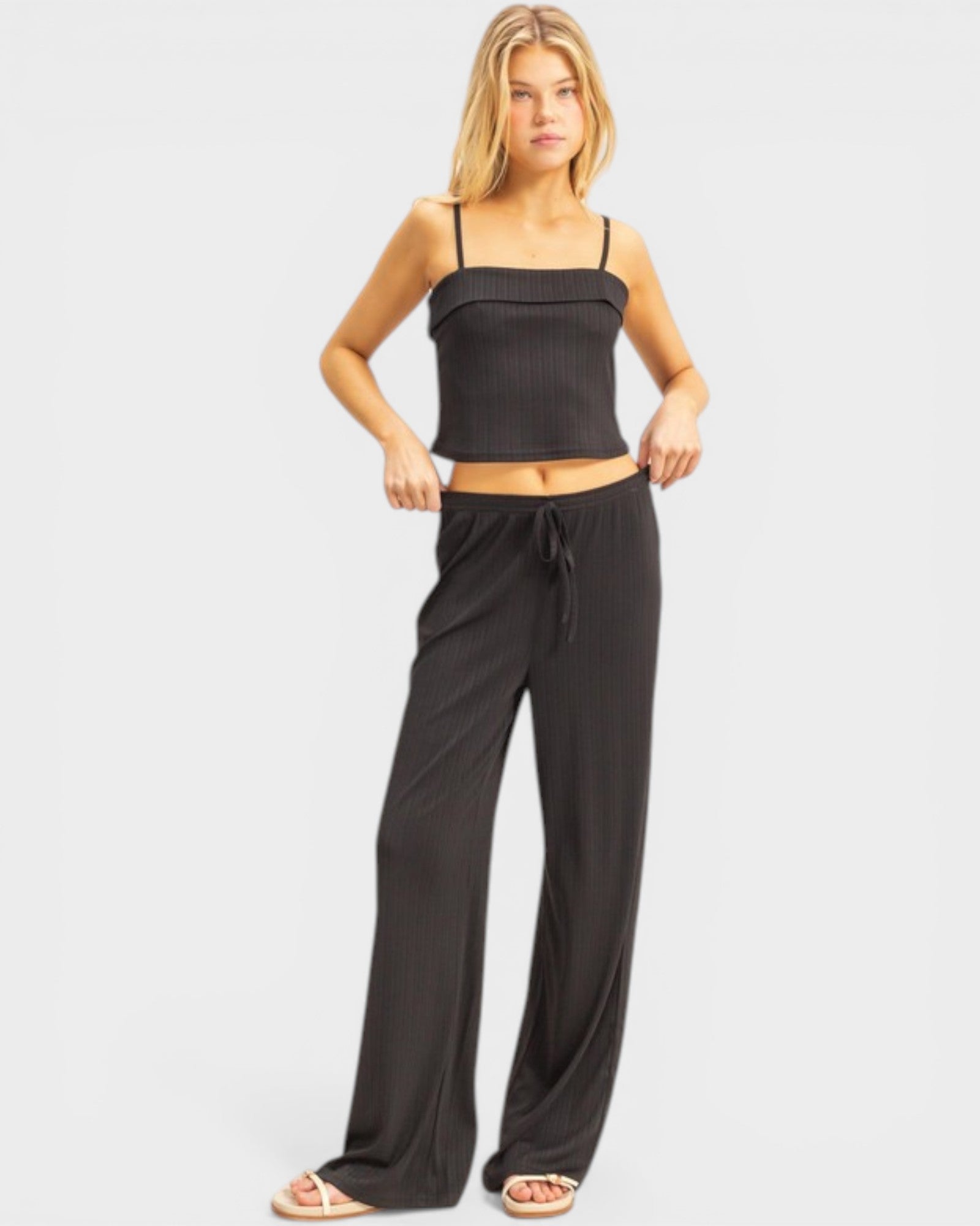 Woman wearing a black top and wide-leg pants on a white background