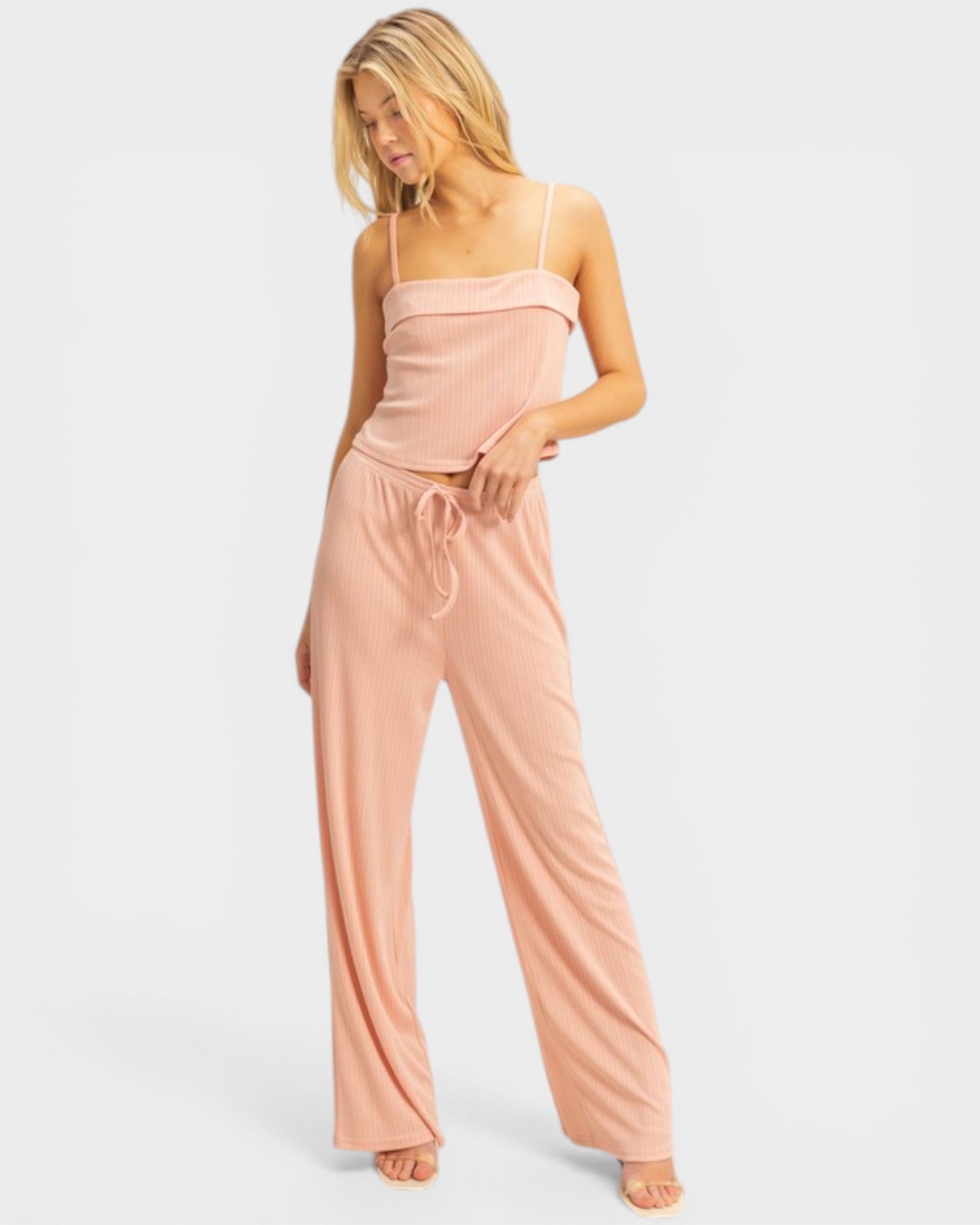 Woman wearing a pink strapless jumpsuit on a light gray background