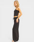Woman wearing a black strapless top and wide-leg pants on a white background