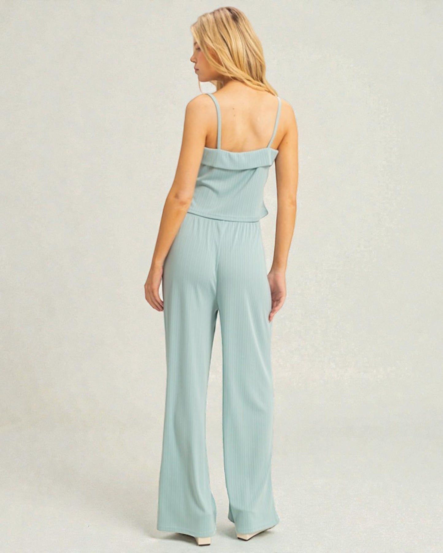 Woman wearing a light blue jumpsuit on a plain background