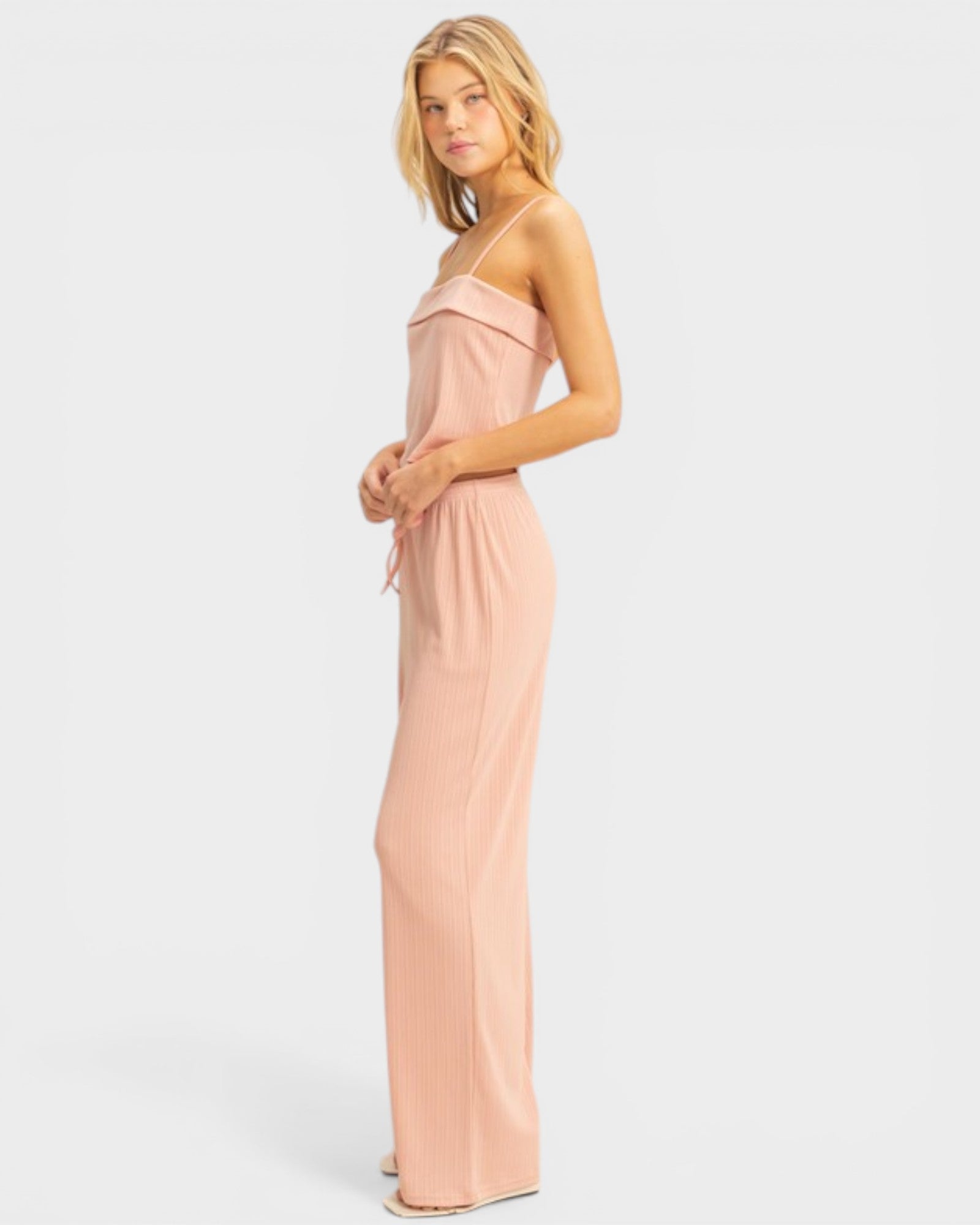 Woman wearing a long, light pink dress against a white background