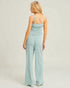 Woman wearing a light blue jumpsuit on a plain background