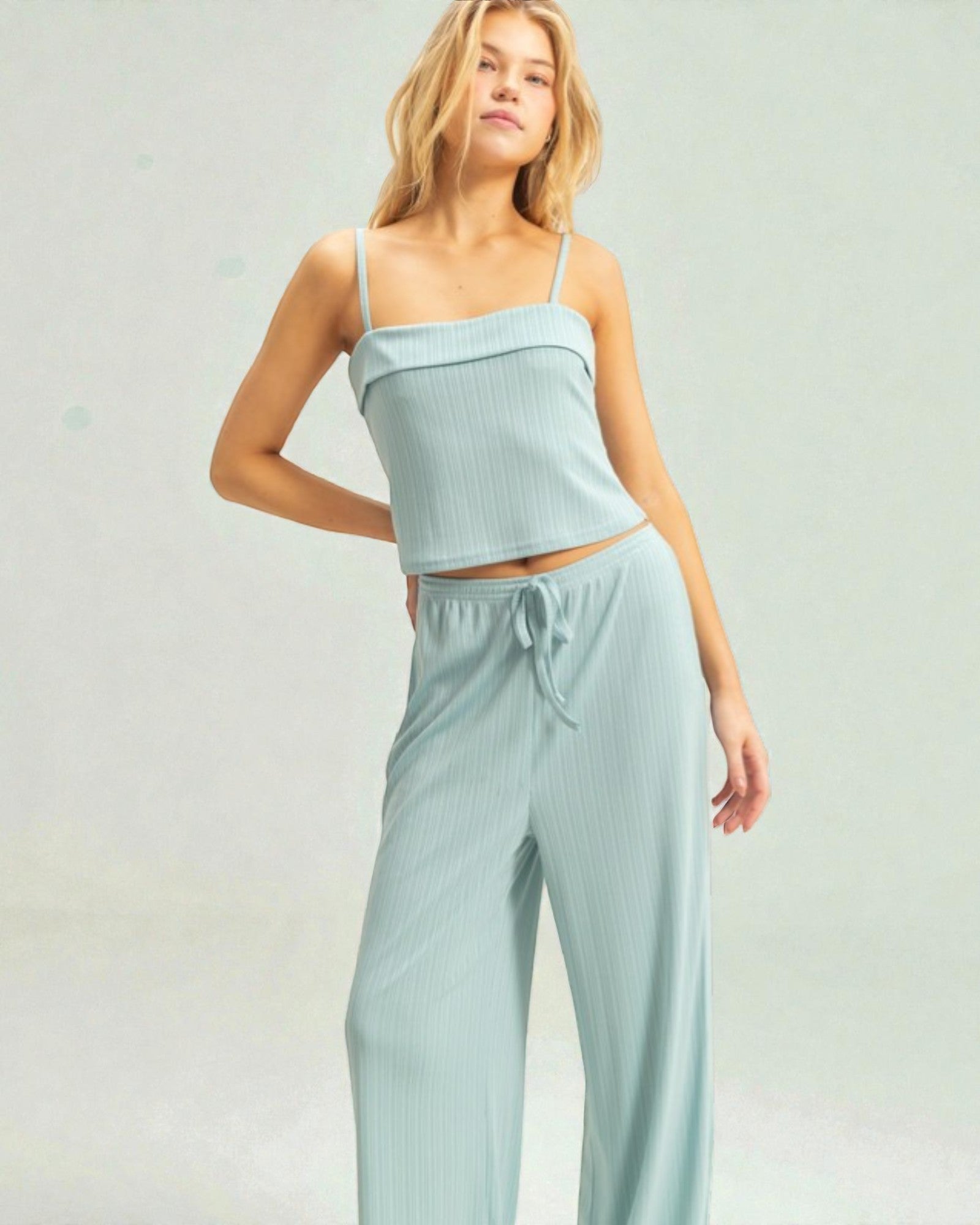 Woman wearing a light blue top and pants set on a plain background