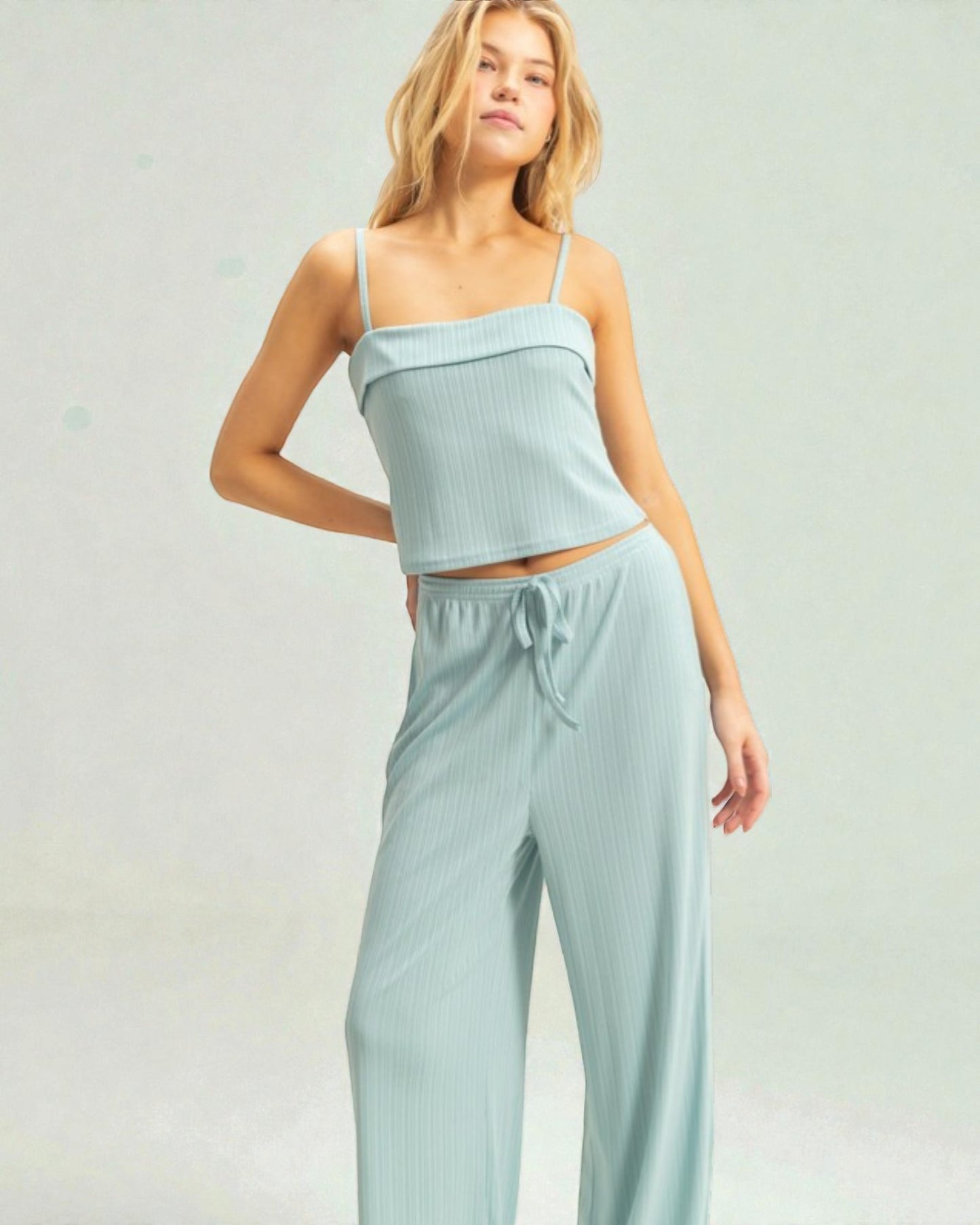 Woman wearing a light blue top and pants set on a plain background