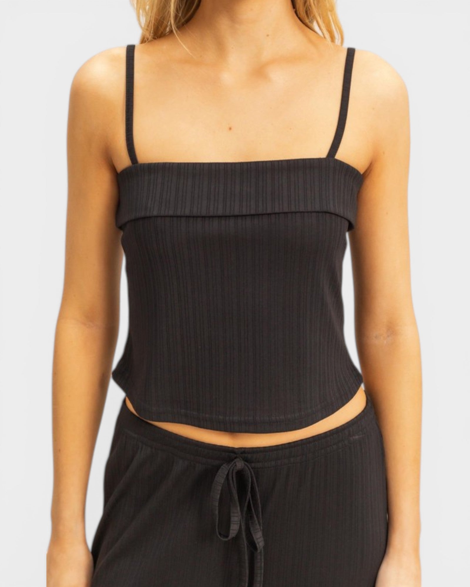 Black ribbed tank top worn by a person on a plain background