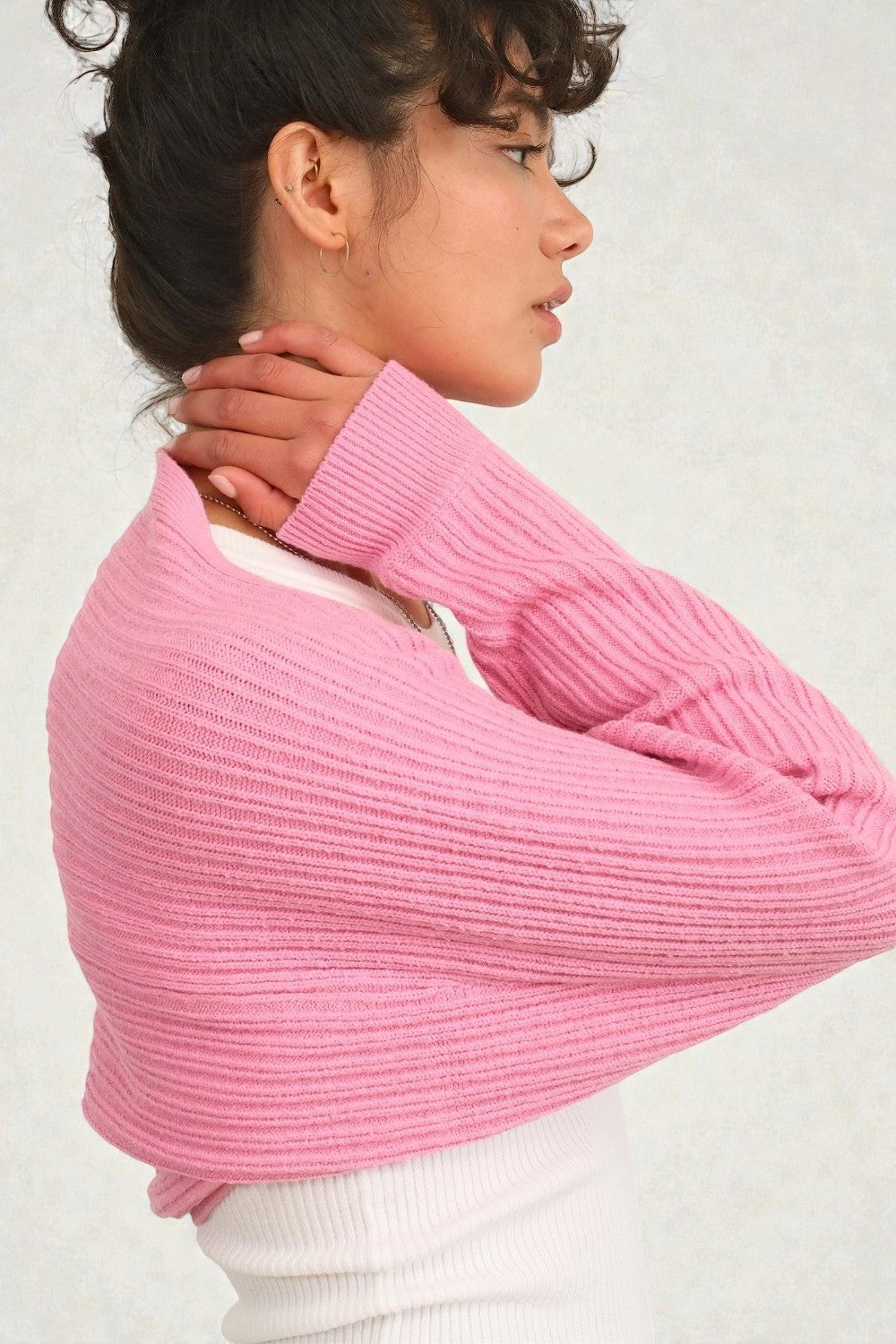 Person wearing a pink sweater against a plain background