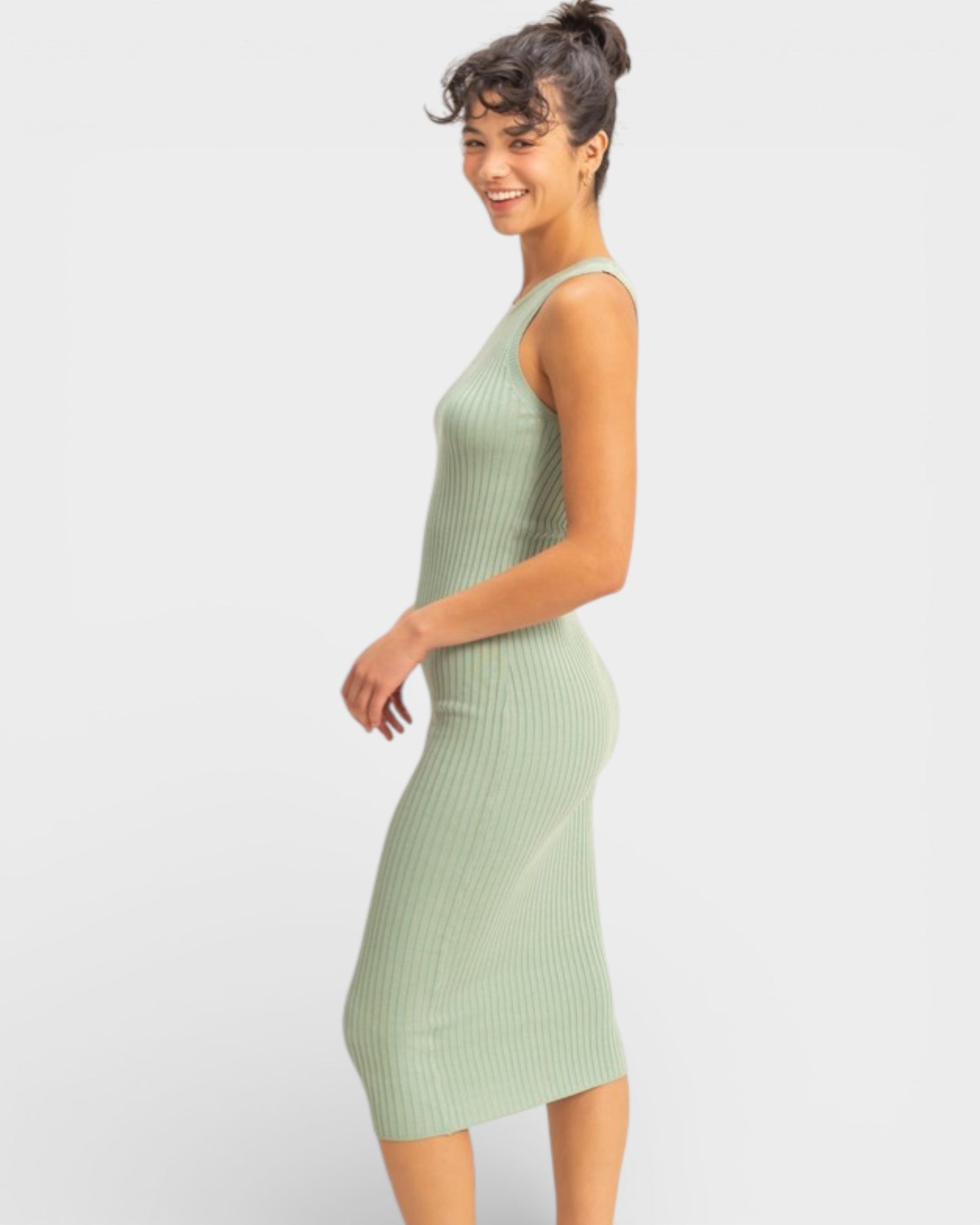 Woman wearing a light green ribbed dress against a white background