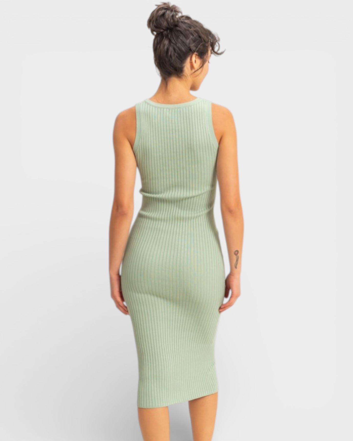 Woman wearing a light green ribbed dress on a white background