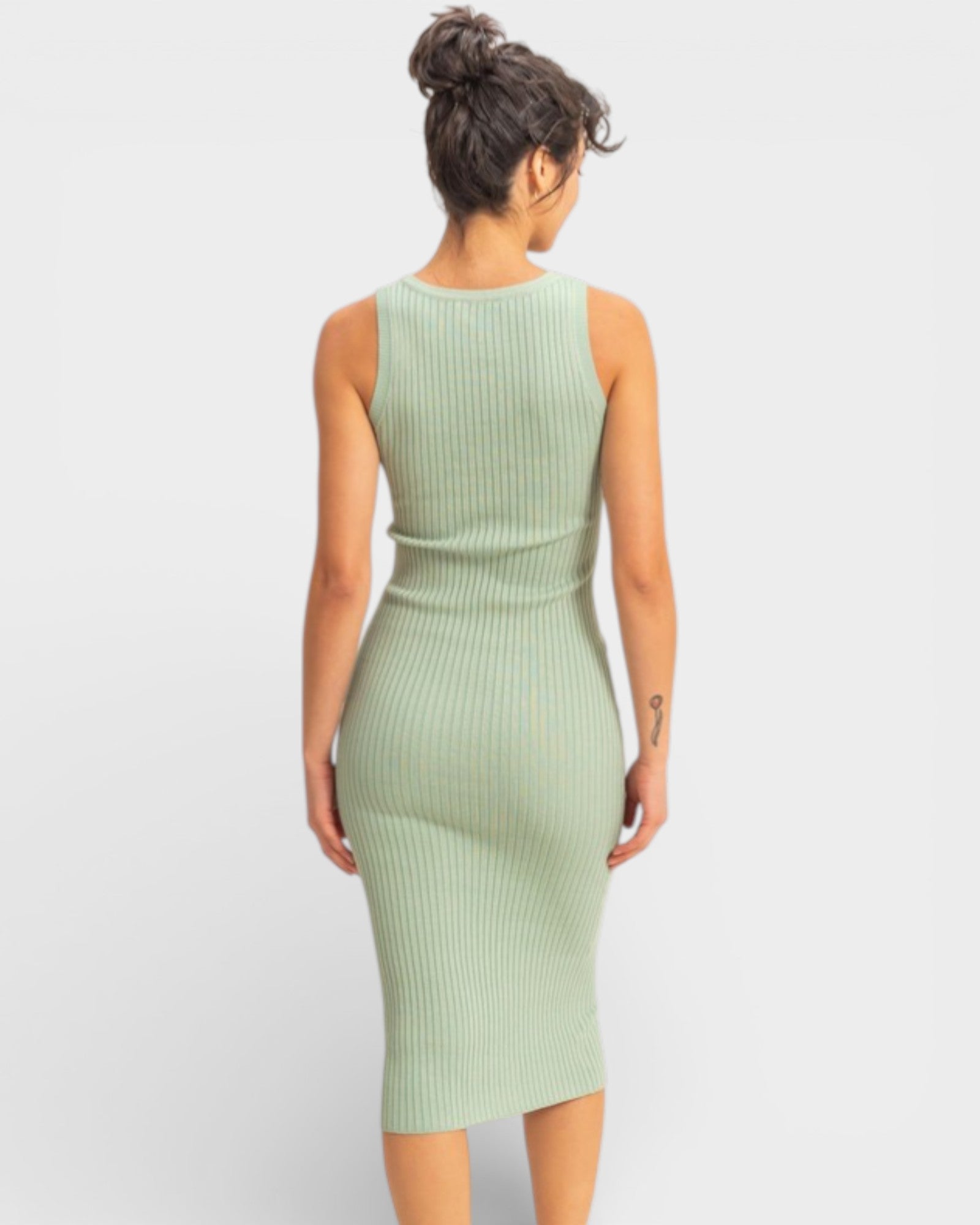 Woman wearing a light green ribbed dress on a white background