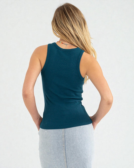 Woman wearing a teal tank top and light blue jeans on a white background