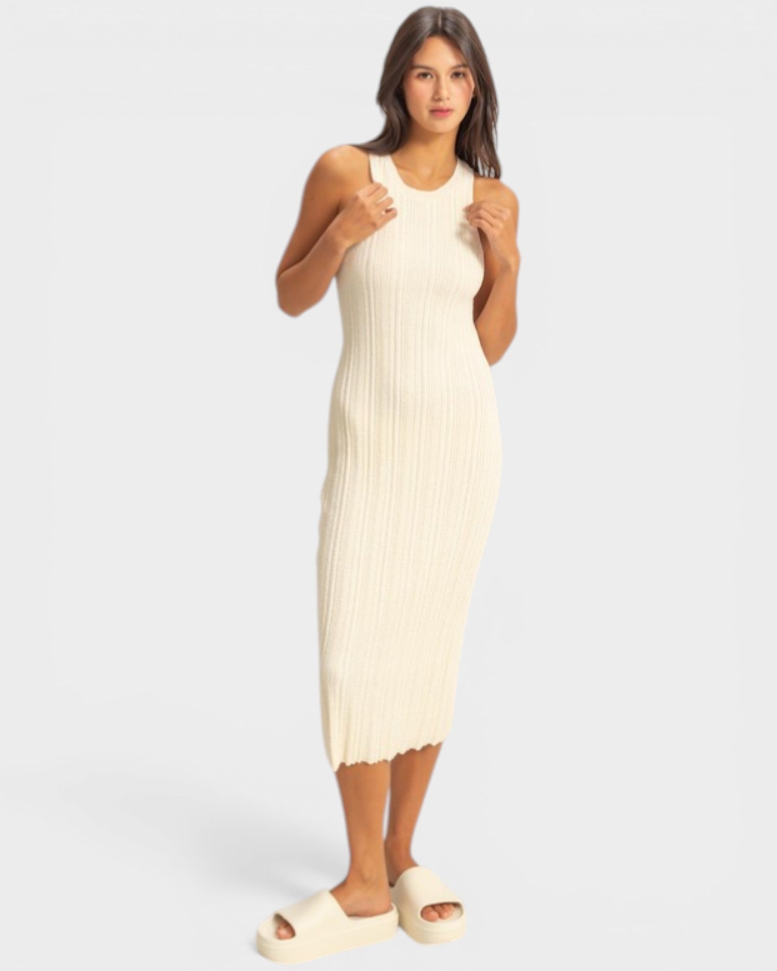 Woman wearing a cream ribbed dress against a white background