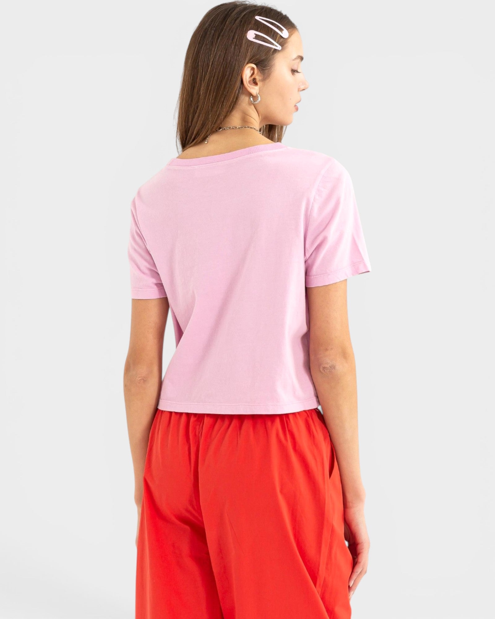 Person wearing a pink top and red pants on a white background