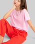 Woman wearing a pink top and red pants on a gray background