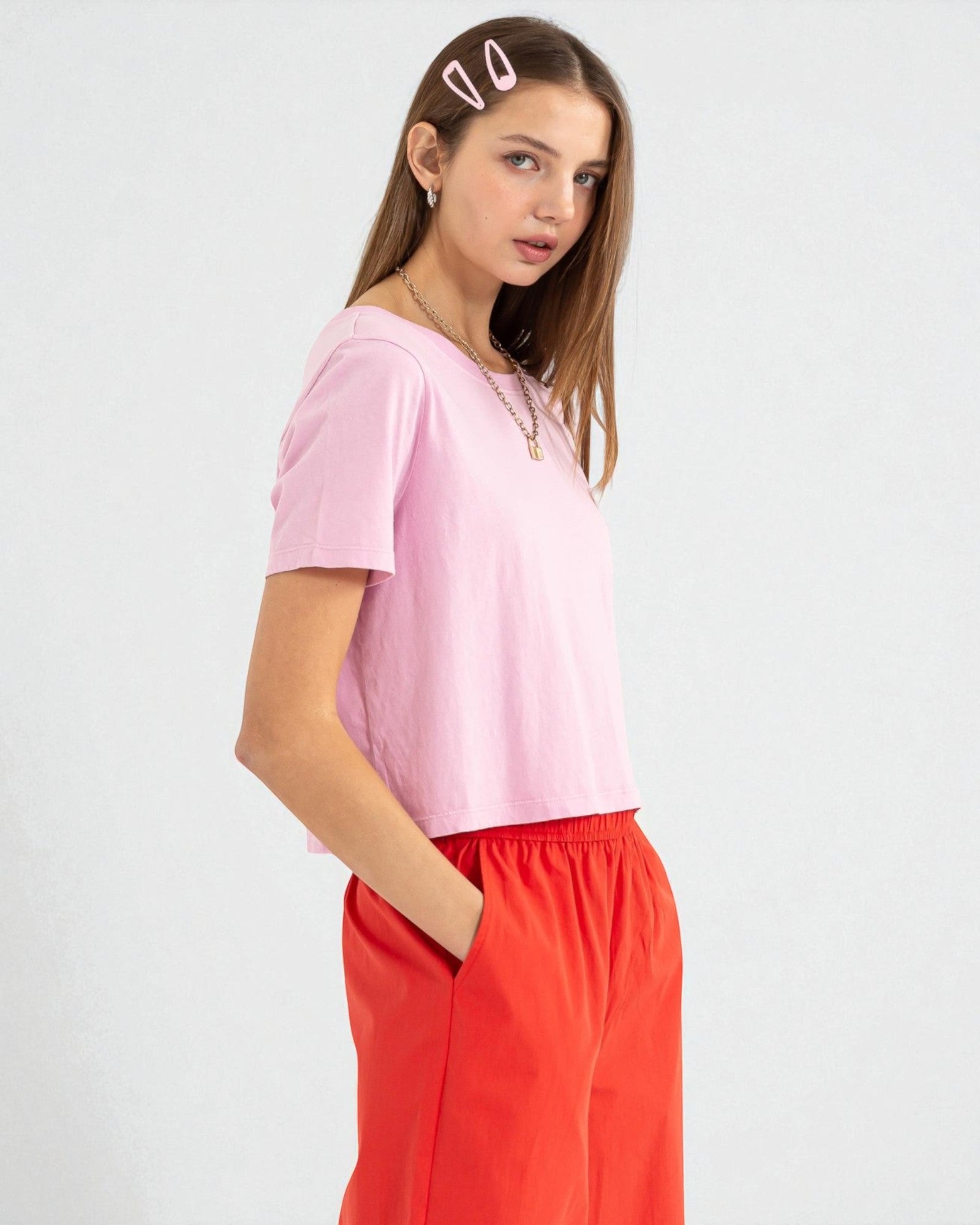 Woman wearing a pink top and red pants on a white background